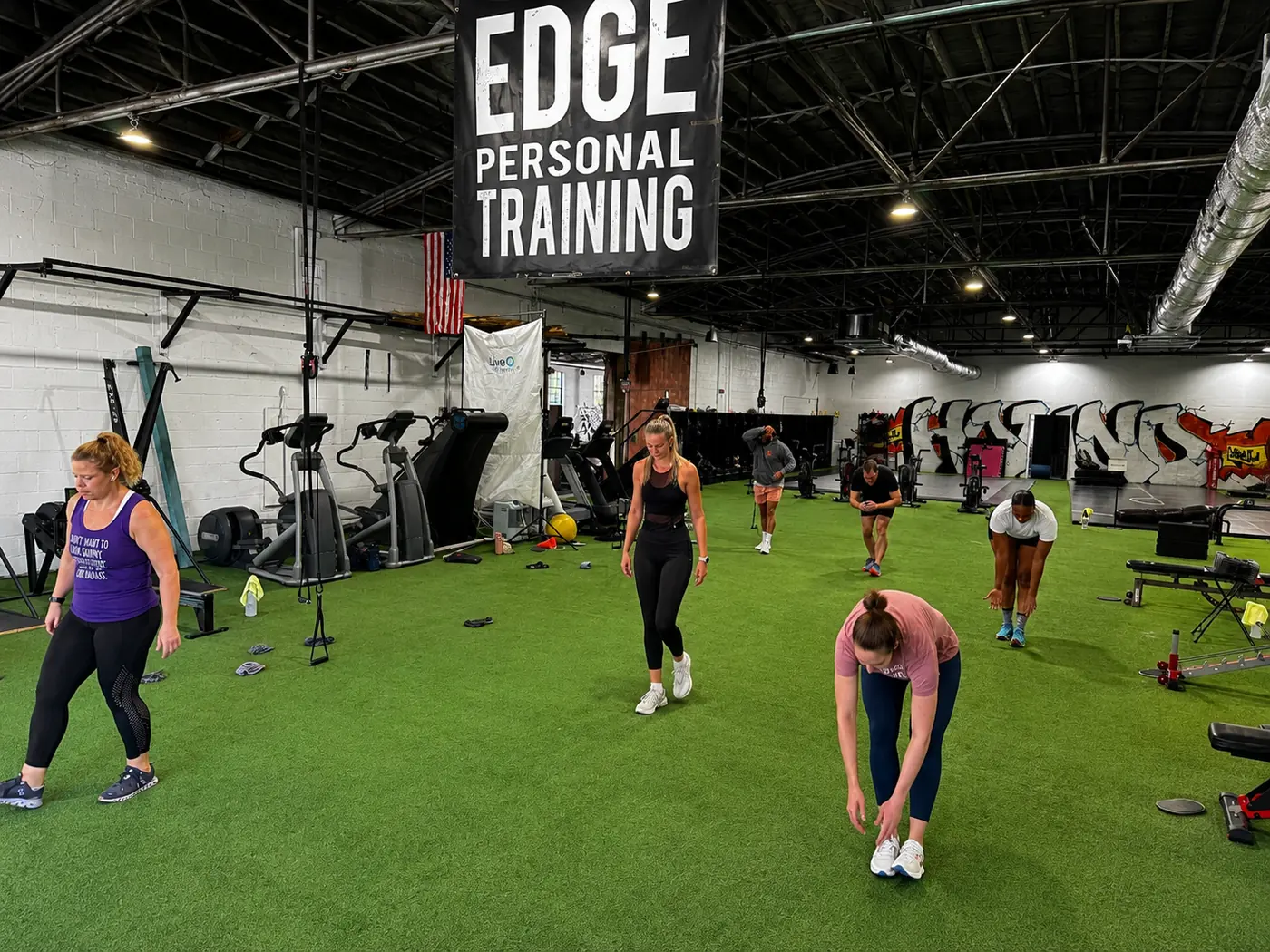 An EDGE coach crouched alongside a client, coaching them through a floor exercise